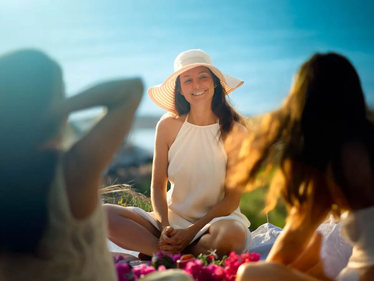 Retreat on Madeira: participants sitting in a circle on a blanket with flowers by the sea